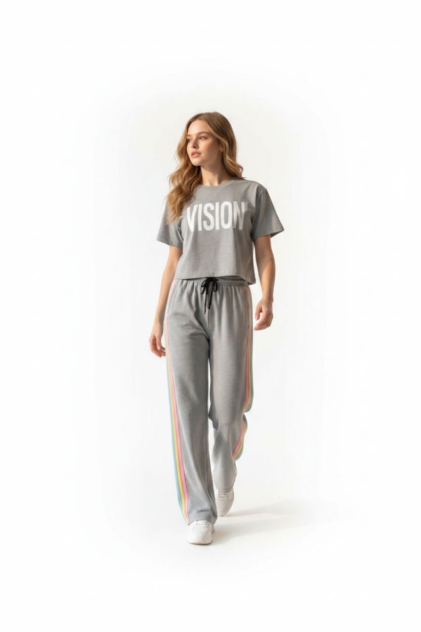 Woman wearing a gray 'VISION' t-shirt and pants with rainbow stripes on a white background